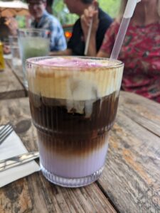 a fancy coffee that is a layer of pale purple then dark brown then creamy white