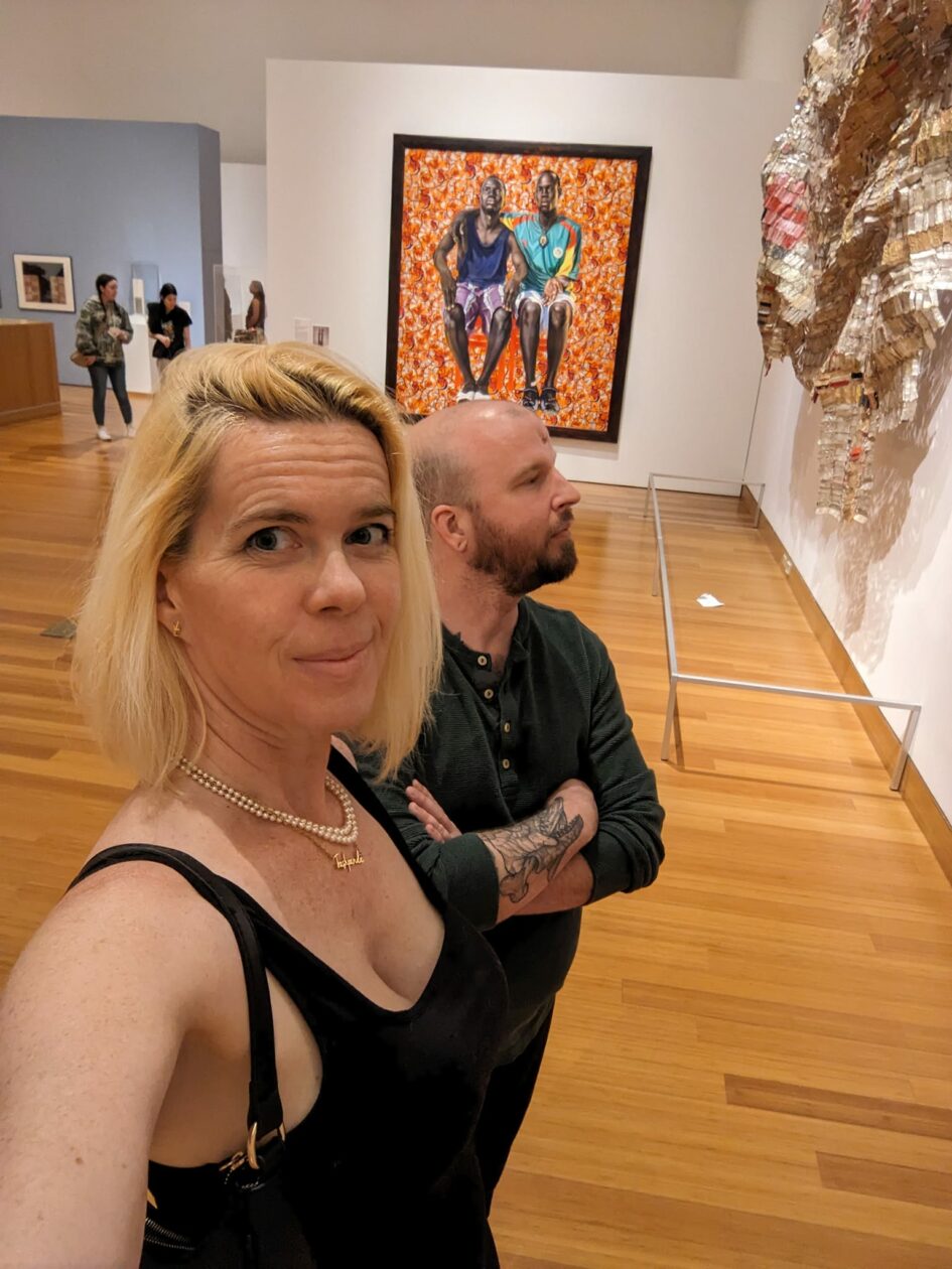 a selfie of two people looking at huge wall art in a museum