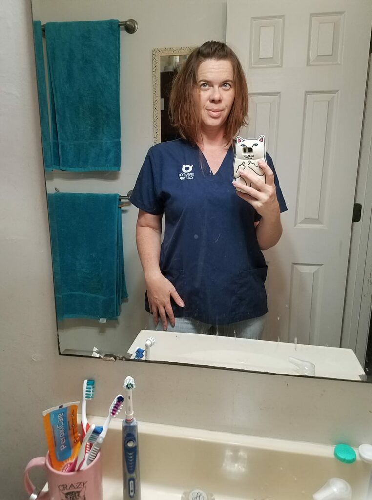 bathroom selfie wearing dark scrubs and jeans