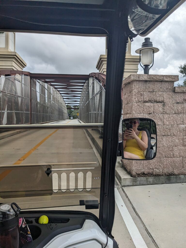 a view out the front of a golf cart with a small bridge incline ahead
