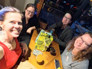 four people sit around a table in what seems like a brewery