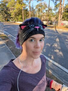 selfie of a person running on a city street and wearing a headband with a cat face and ears