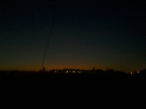 a very blurry picture of a dark sunrise and possibly lights from homes in the distance