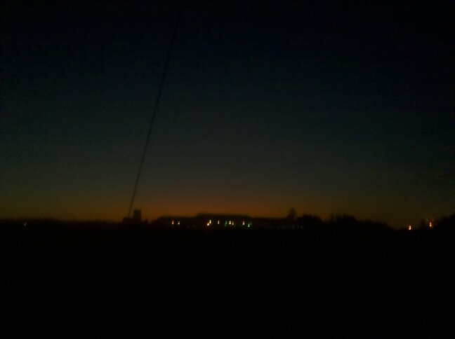 a very blurry picture of a dark sunrise and possibly lights from homes in the distance