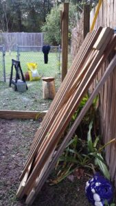long wooden planks are leaning on a fence in a yard