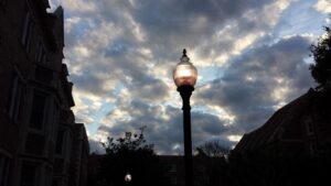 buildings and a street light are silhouette against a cloudy morning sky