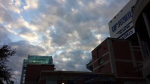 a sports stadium of some kind with a gator logo on it has a bright morning sky behind it
