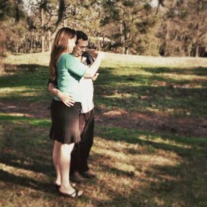 two people have arms draped over each other and are looking at something in their hands