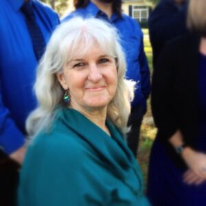 a woman with flowing silver hair is smiling into the camera