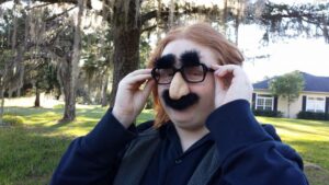 a redhead boy wearing novelty glasses with a fake nose and mustache