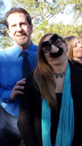 a man standing next to a girl wearing novelty glasses with a fake nose and mustache