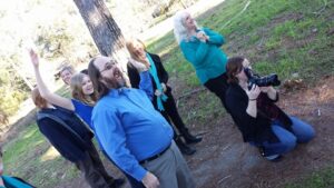 a group of people making faces off camera while a person kneels to take pictures in that direction
