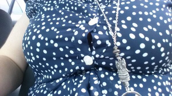 close up of the front of a polka dot blouse with the gap between buttons straining