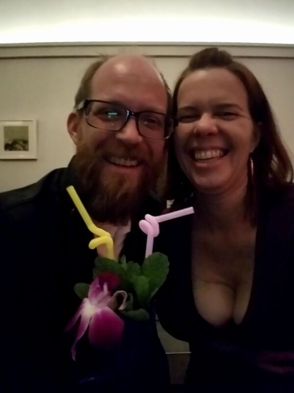 a dark blurry selfie of two people with fancy cocktails
