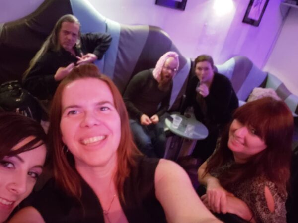 a group of people making faces at the camera in some kind of bar or club with vibrant red and blue lighting
