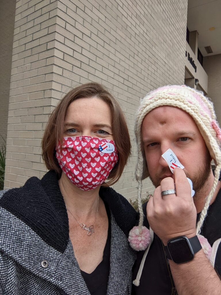 selfie of two people in coats and hate wearing I Voted stickers