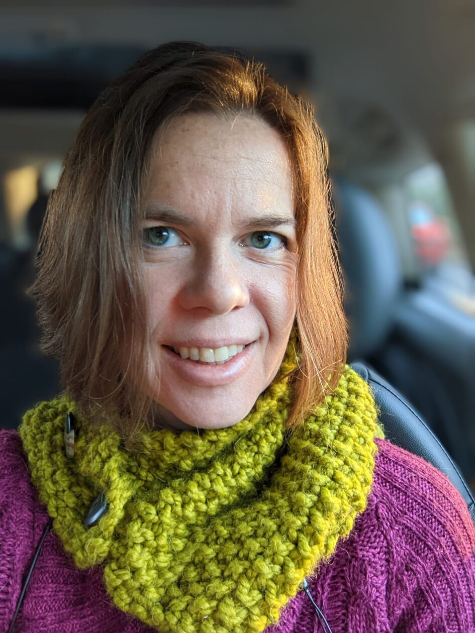 selfie of someone in a car with nice lighting to show their green scarf against their purple sweater