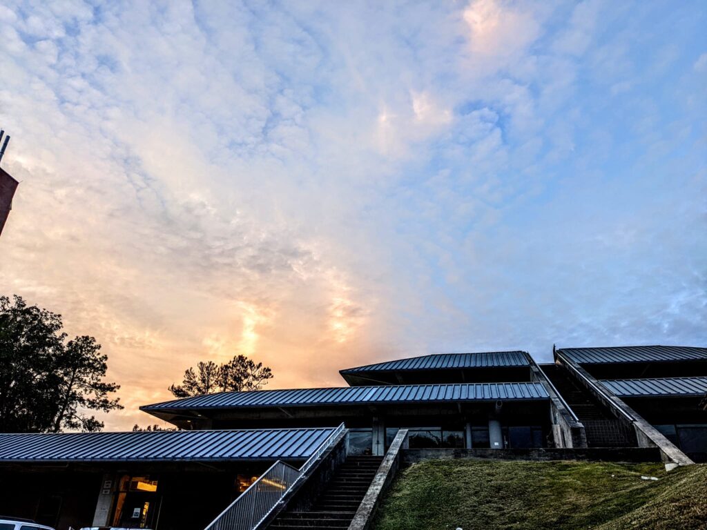 a broad sky shot with crumbly clouds over a building with angular lines and steep stairs looking somewhat futuristic
