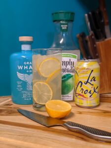 a kitchen counter with a knife and lemon and a bottle of gin with juice and other mixers