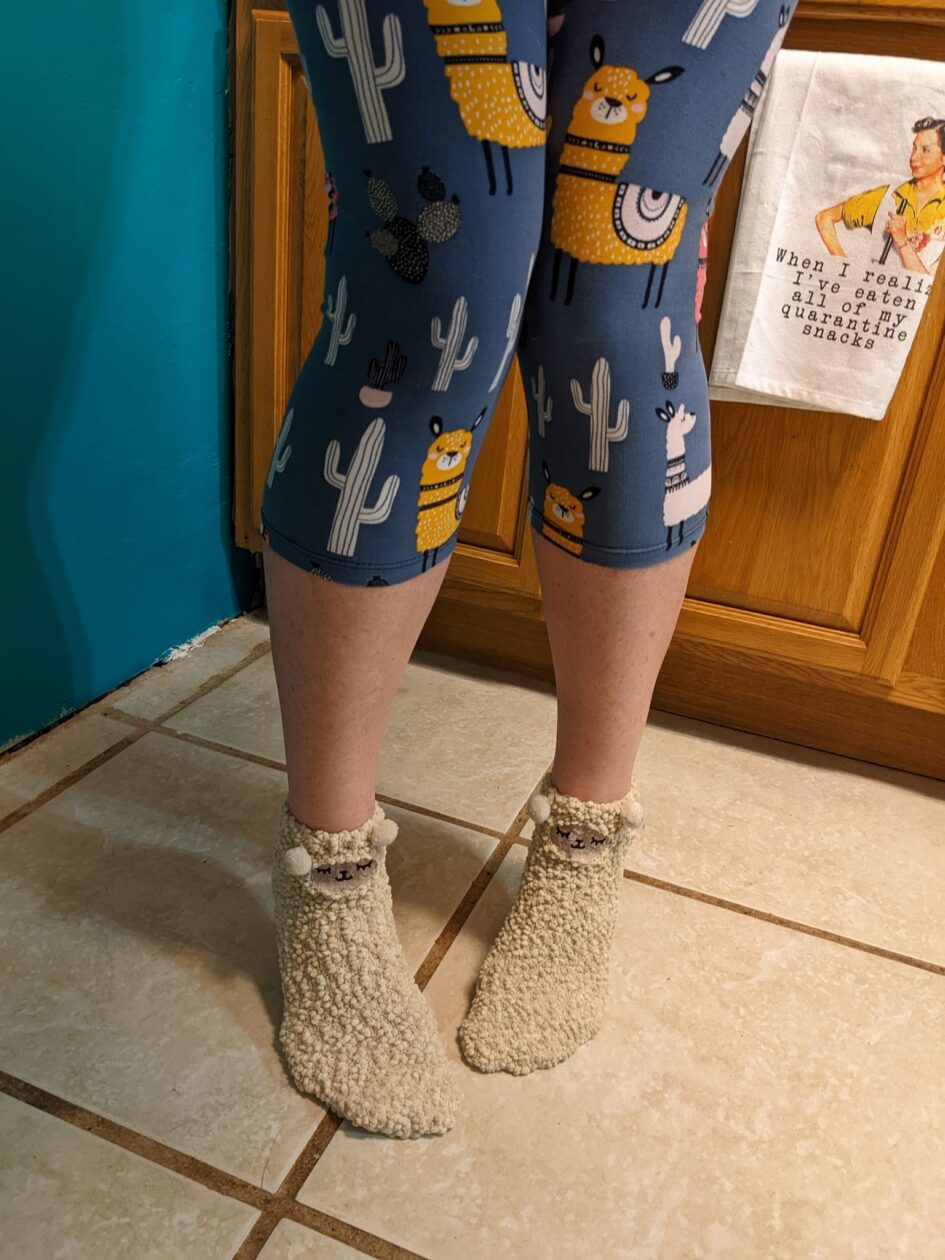 someone's legs covered in leggings printed with cactuses and llamas and socks that could be llamas too