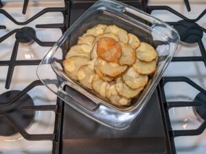 a stovetop with a casserole dish covered in potato slices