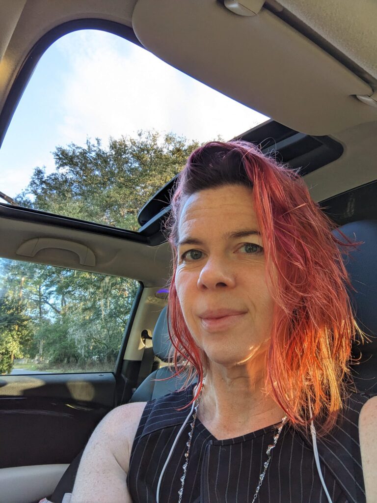 a selfie of someone with very red hair in a car with sunlight coming in sideways
