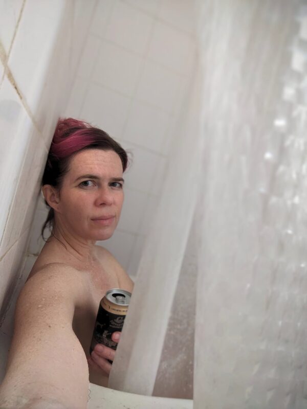 selfie of someone sitting in a shower holding a beer