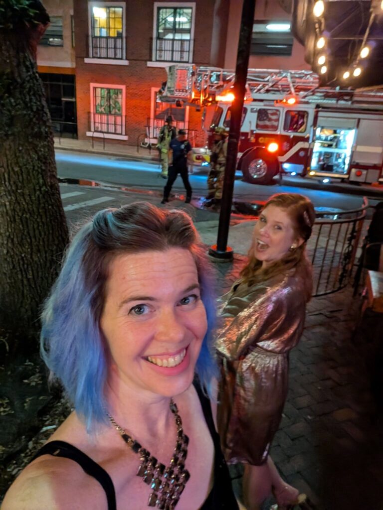 two people dressed up are looking at a fire truck in a city street