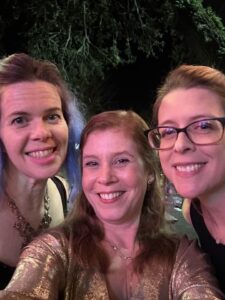 three ladies are dressed up at night