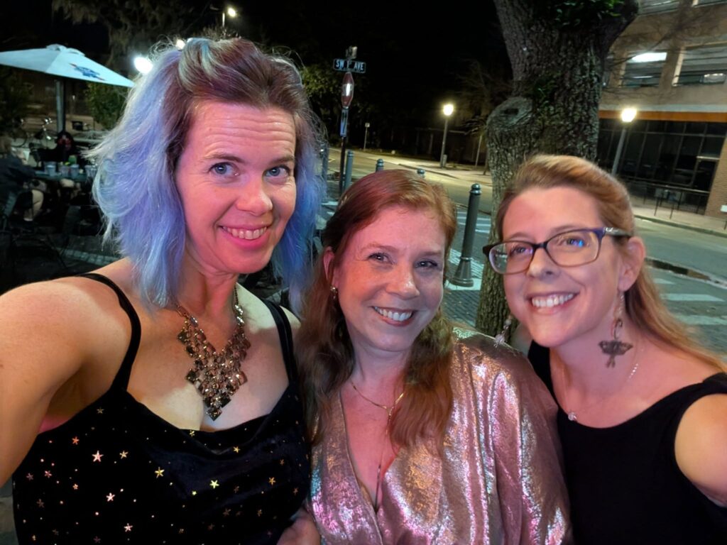 three ladies are dressed up on a night city street