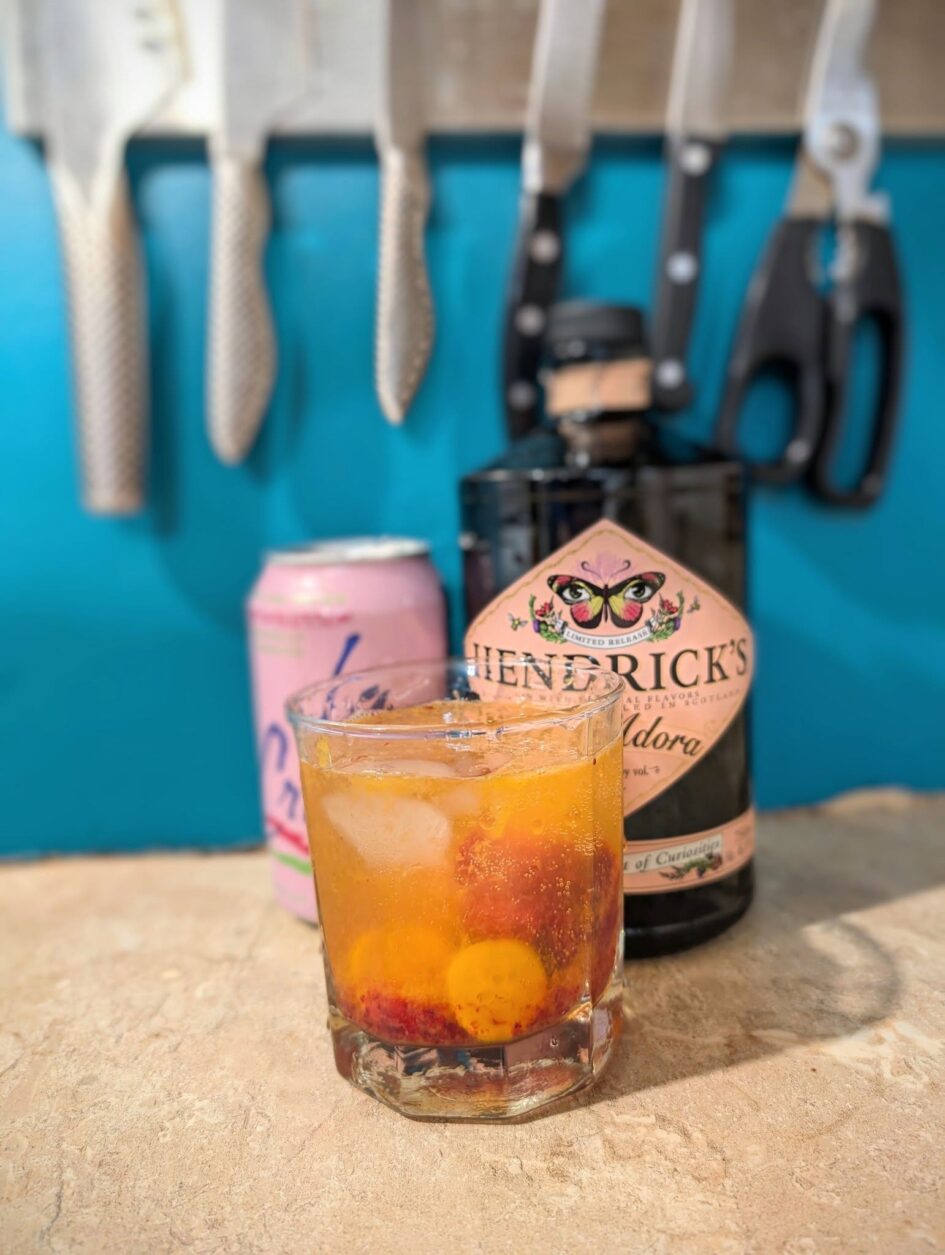a bottle of hendrick's gin and soda is behind a cocktail glass