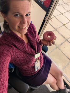 a person is sitting back in an office chair about to eat a donut