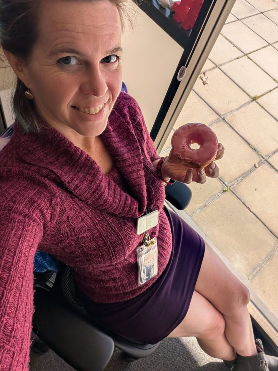 a person is sitting back in an office chair about to eat a donut