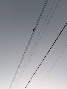 three birds sit next to each other on a row of power lines far above