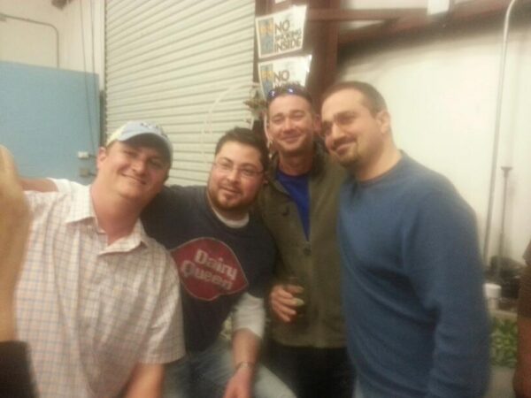 four men in casual clothes are crowded together for a photo