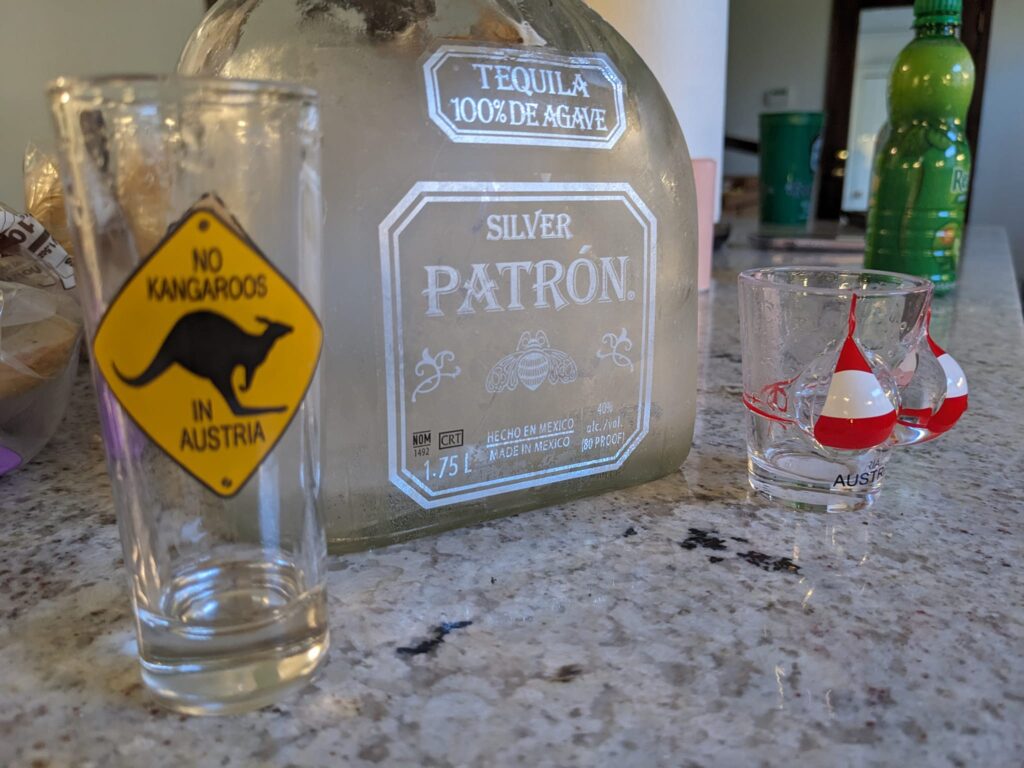 two tacky shot glasses next to an empty bottle of Patron tequila