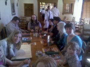 a very blurry picture of a dozen people at a table in a restaurant with servers in the background