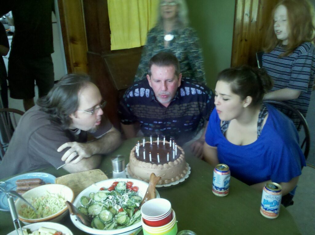 a blurry picture of three people bending in to blow out the candles on a cake