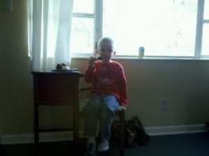 a child is sitting on a wooden seat under a big window eating something
