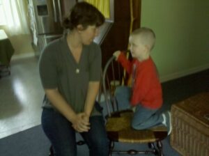 a child is sitting on a wooden chair talking to an adult sitting in a chair next to him