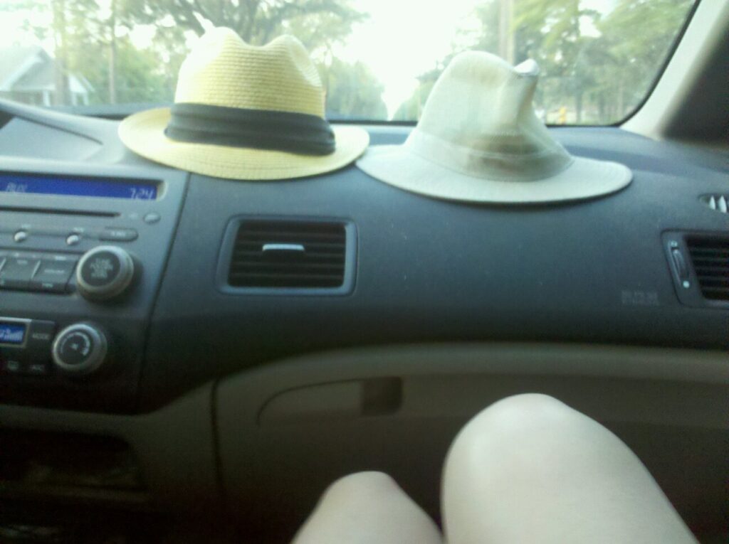 a car dash board has two tan hats resting on it