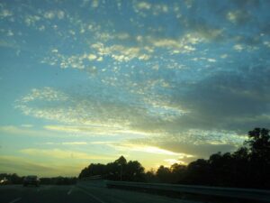 a sunset over a highway is illuminating tiny clouds that look like confetti