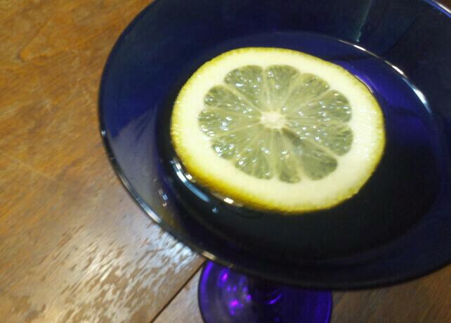 a lemon slice floats in a deep cobalt blue martini glass