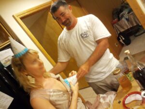 a person is holding a pointed birthday hat over another person's breast jokingly and the woman is making a negative face