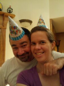two people in birthday hats are smiling for the camera
