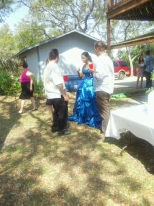 several people with red solo cups standing around outside with one in a formal blue dress