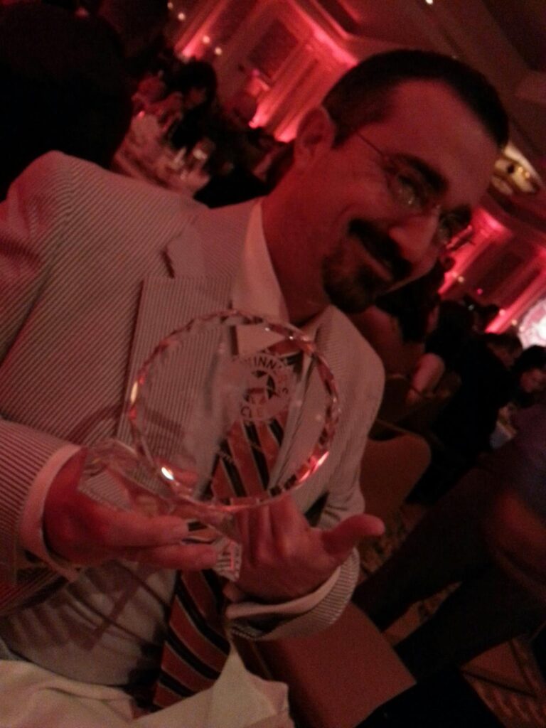 a person in a suite is holding a large glass disk that is probably an award