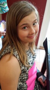 a child is smiling for the camera and holding her wrist in a cast