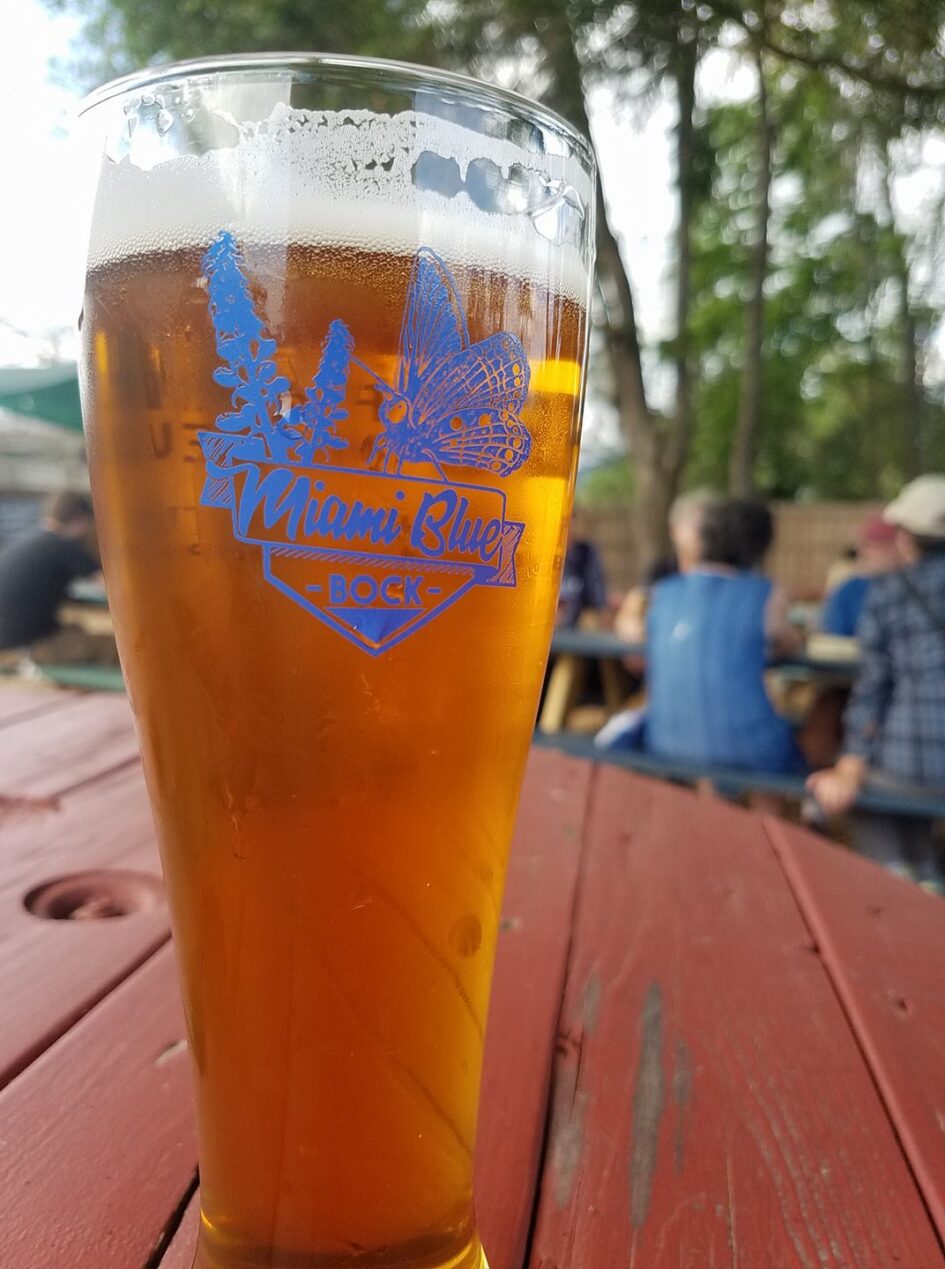 a tall glass of beer with a logo and the words miami blue on it