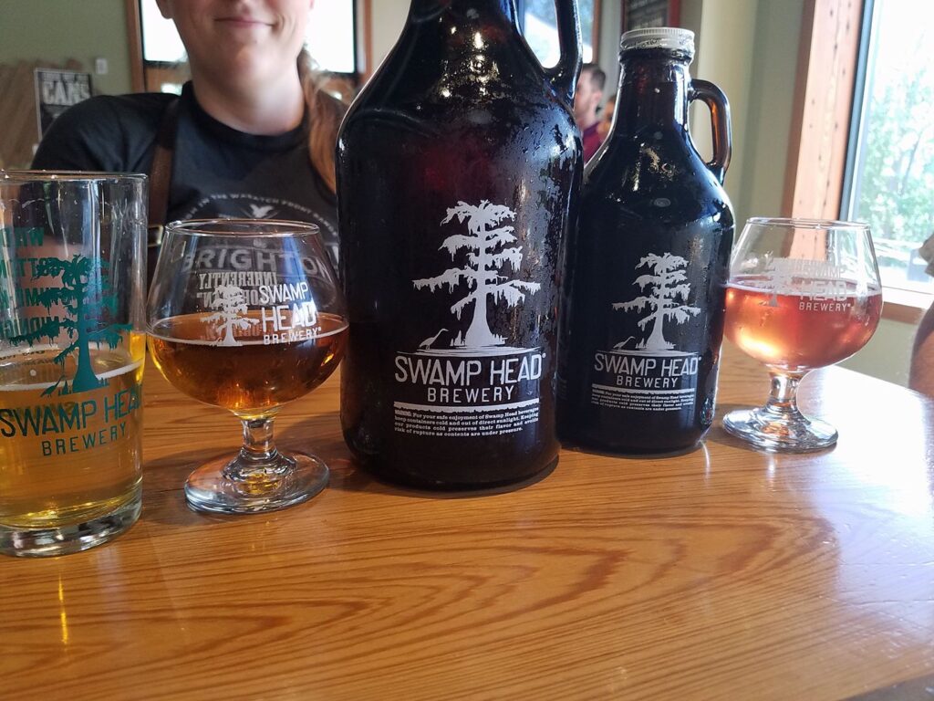 a row of beer glasses and beer growlers on a wooden table